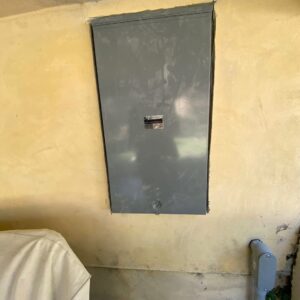 A closed electrical panel recessed into a yellow wall, indicating a completed installation by Prime Electric in Bellevue, WA.