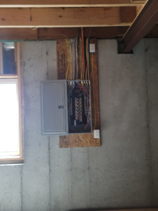 An open electrical panel with wiring installed on a concrete wall by Safehouse Electric Company in Blue Springs, MO.