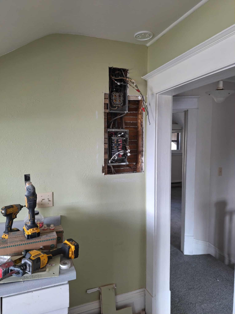 An electrical panel being installed in a wall, with electrician tools nearby, by Candid Electric in Spokane, WA.