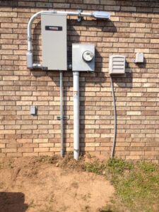 Electrical panel and meter base installation on a brick wall by Corley Electric & Automatic Power Solutions in Fort Smith, AR.