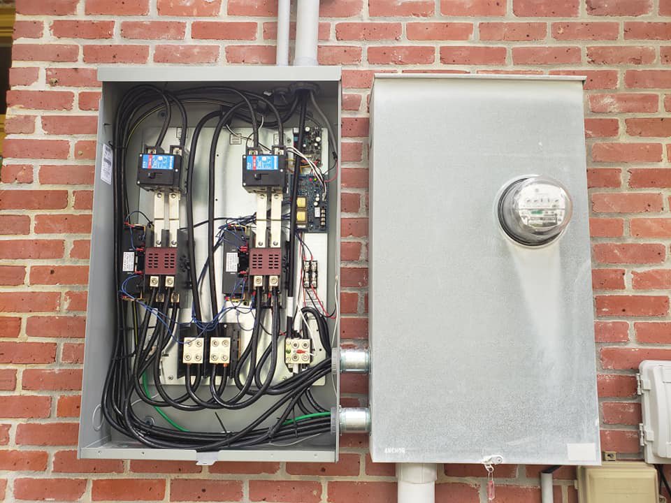 An open electrical panel and meter showing wiring on a brick wall, installed by K-Gen Electrical and Generator Services in Houma, LA.