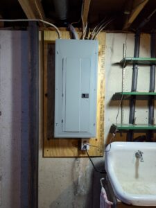 An electrical panel installed on a wooden board in a utility room by Jeremy Electrical in Roeland Park, KS.
