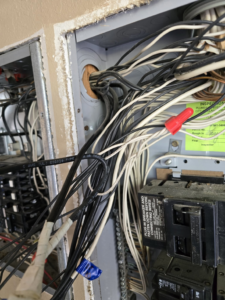 Close-up of an open electrical panel with complex wiring and circuit breakers by Hummingbird Electric Inc. in Tulsa, OK.
