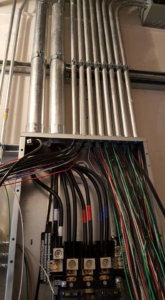 An electrical panel with complex wiring and conduit installation by Genesys Electrical Contractors in Dallas, TX
