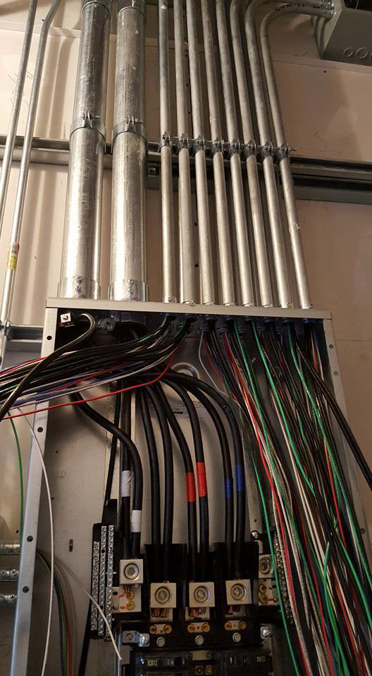 An electrical panel with complex wiring and conduit installation by Genesys Electrical Contractors in Dallas, TX