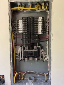 An electrical panel during wiring installation, showing neatly organized wires and circuit breakers by Ozzy Electric in Jacksonville, FL.