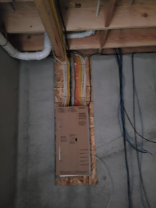 A closed electrical panel with multiple wires installed on a concrete wall by Safehouse Electric Company in Blue Springs, MO.