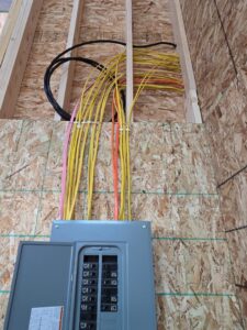 An electrical panel with wires running into it, installed in a framed wall by Trademark Elite Electrical Services in Butte, MT