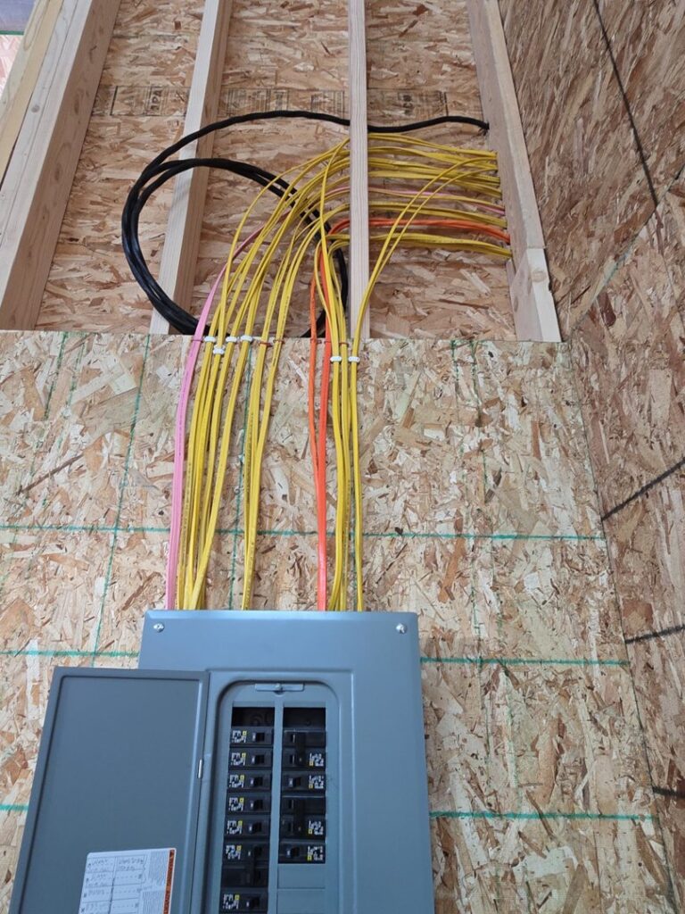 An electrical panel with wires running into it, installed in a framed wall by Trademark Elite Electrical Services in Butte, MT