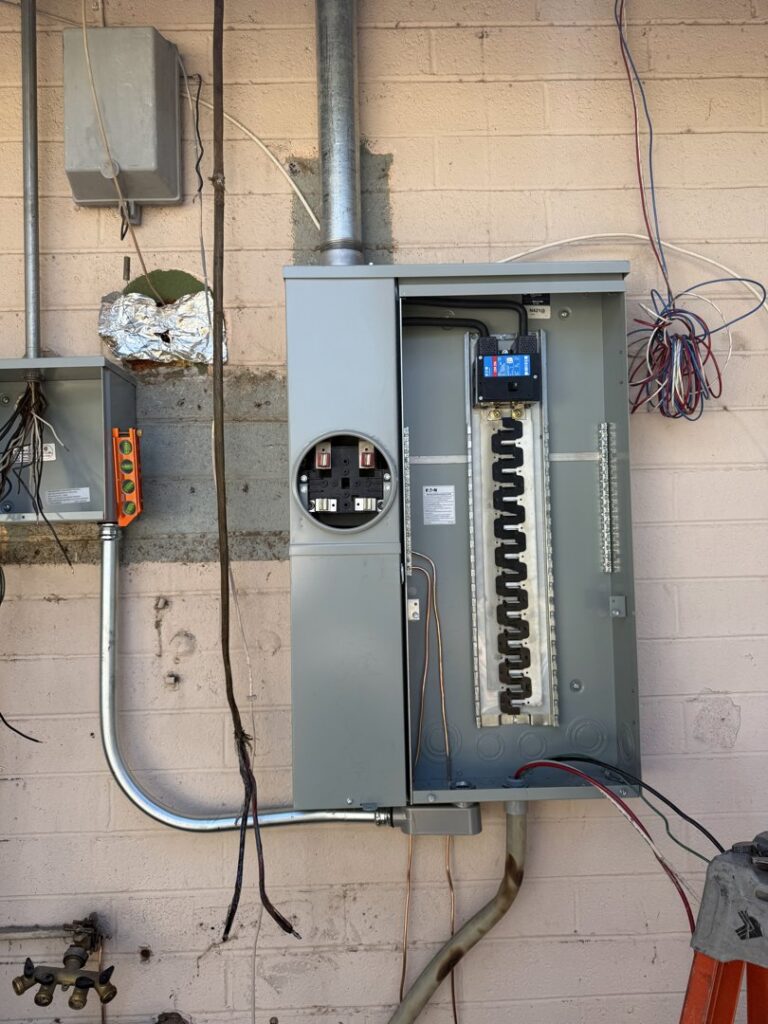 An outdoor electrical panel with exposed wiring, showing ongoing electrical work by TAP and Sons Electric in Tempe, AZ.
