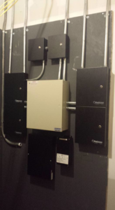 Electrical panels, conduits, and wiring installed on a wall by Triple G Electrical Services in Alabaster, AL