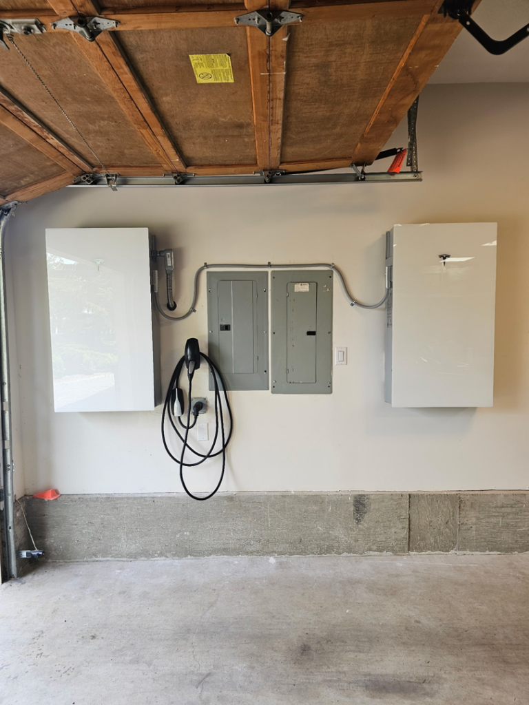 Multiple electrical panels, an EV charger, and energy storage units installed in a garage by ANT POWER LLC in Tacoma, WA.