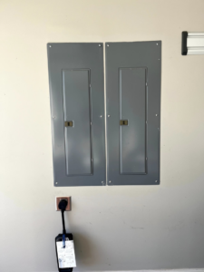 Two electrical panels and an EV charger installation on a wall by Mayflower Electric LLC in Knoxville, TN