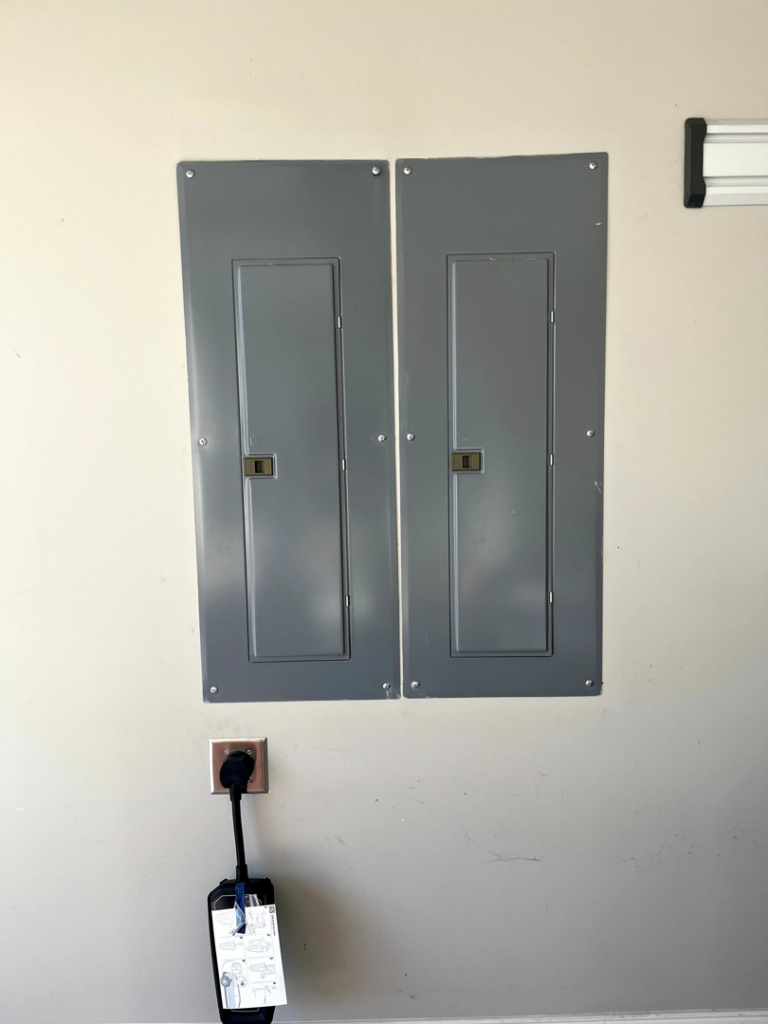 Two electrical panels and an EV charger installation on a wall by Mayflower Electric LLC in Knoxville, TN