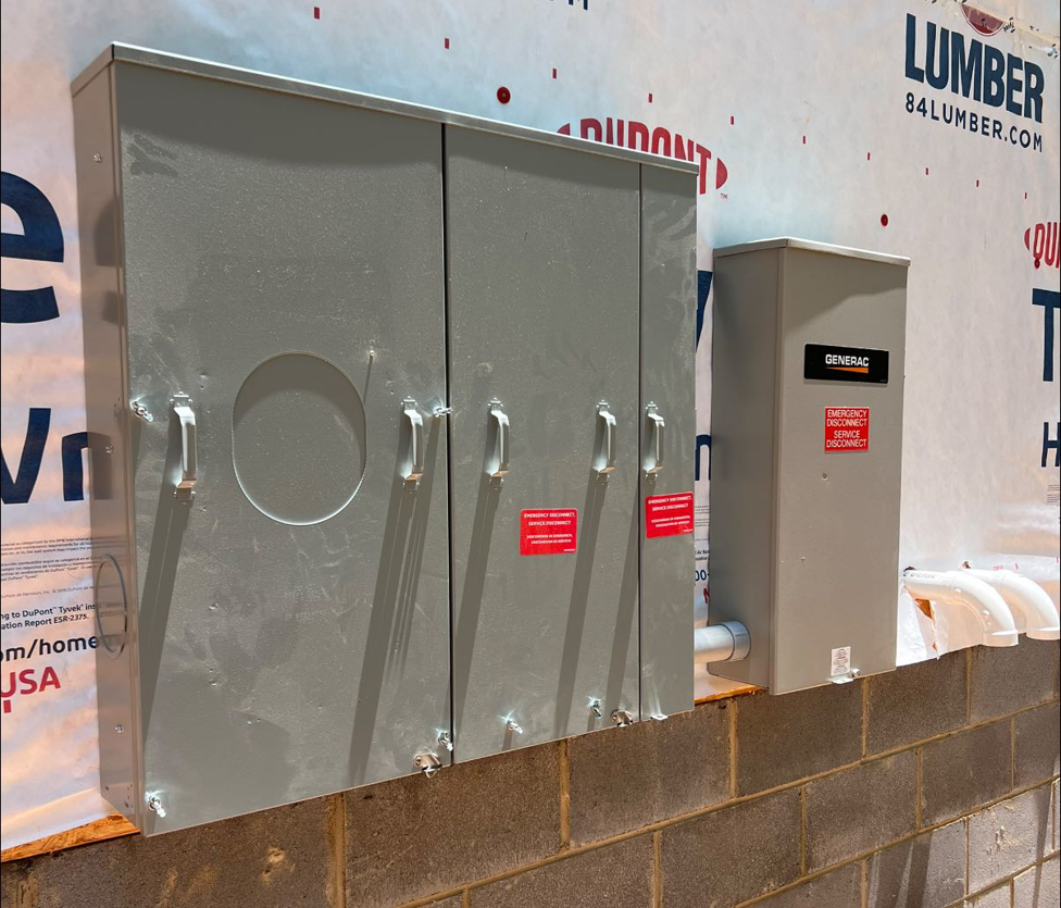 Two large Generac electrical panels installed on the exterior of a building by C.A Electrical & More in Greenville, SC.