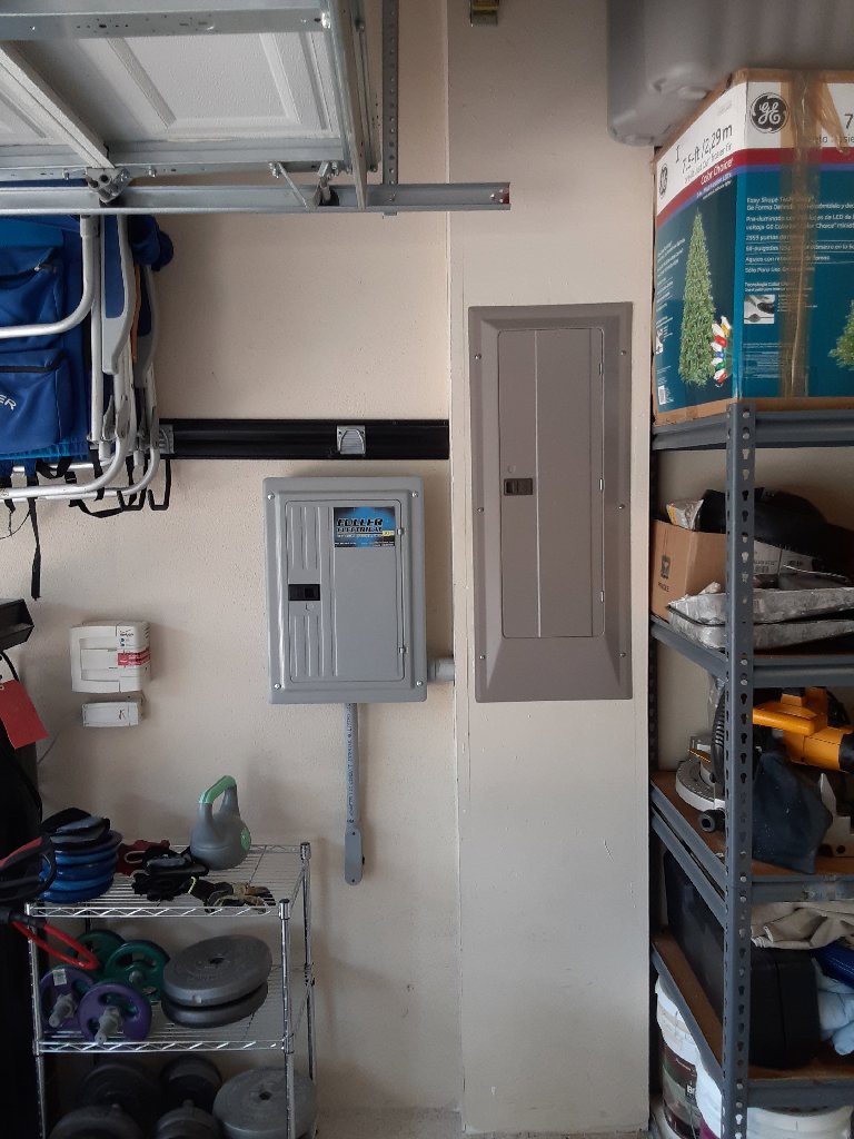 Two electrical panels professionally installed in a garage by Fuller Electrical Contractors, Inc. in Oldsmar, FL.