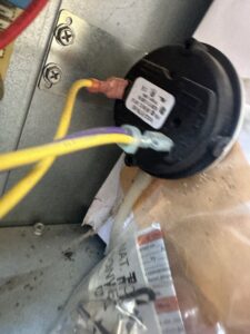 A close-up of an electrical pressure switch with yellow and purple wires connected, serviced by McNeal and Sons Electrical and HVAC in Birmingham, AL.
