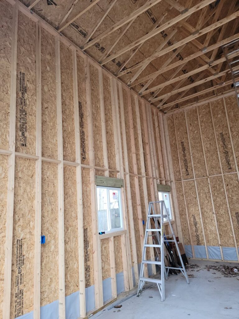 Electrical rough-in work in a new construction room with exposed studs by Neptune Electric in Virginia Beach, VA.