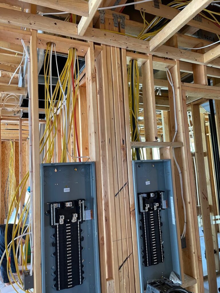 Electrical rough-in with wiring and two breaker panels in a framed wall by Industrial Edge Electrical in Gilbert, AZ.