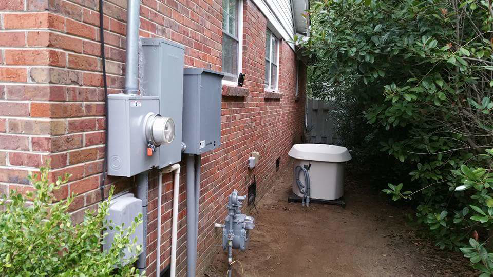 An outdoor electrical service panel and a standby generator installed by Stone Electrical Construction in Florence, SC.