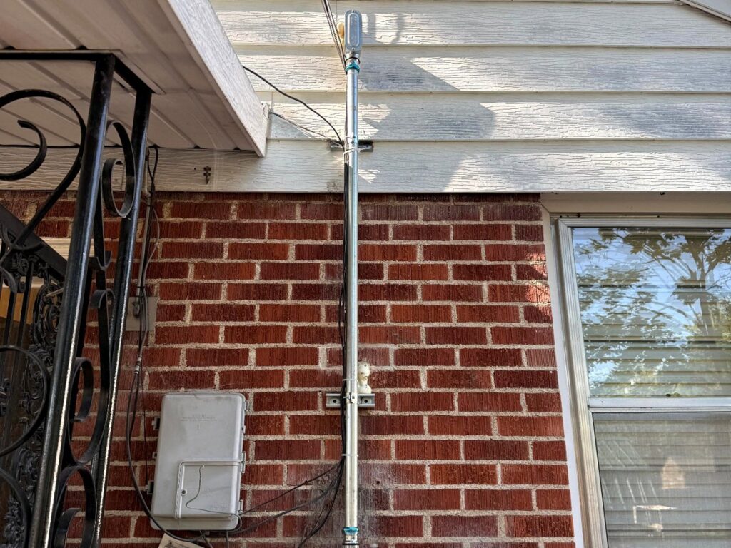 An electrical service mast and meter installed on the brick exterior of a home by Copper Canyon Electric in Farmington, UT.