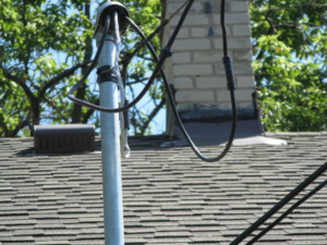 Close-up of an electrical service mast and wires on a residential roof by Mac Electric Company in Warren, MI.