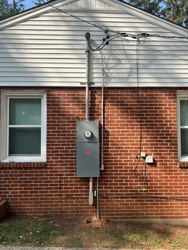 An exterior view of a newly installed electrical service panel and meter on a brick home by Kaufman Electric in Greensboro, NC.