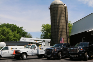 A fleet of electrical service trucks, including a bucket truck, parked outside Ray's Electrical and Boring Service in Elgin, IL.