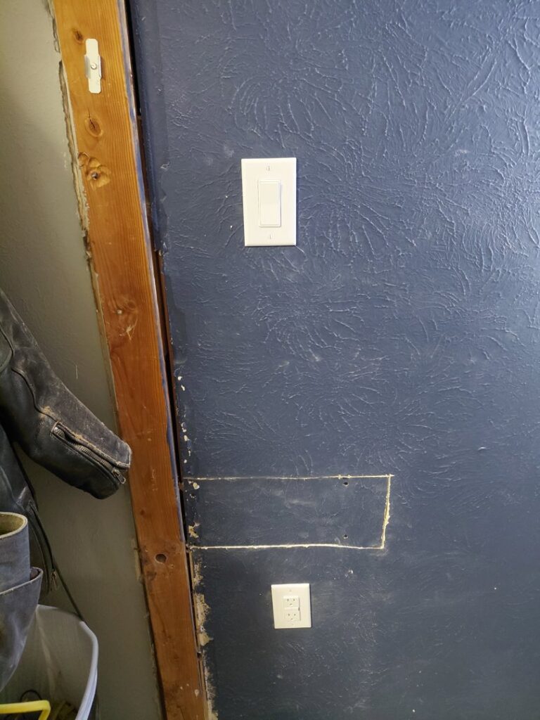An electrical light switch and outlet installed on a blue wall by LE Electric in Las Cruces, NM