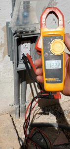 An electrician from Farris Electric LLC testing a GFCI outlet with a multimeter in Glendale, AZ.