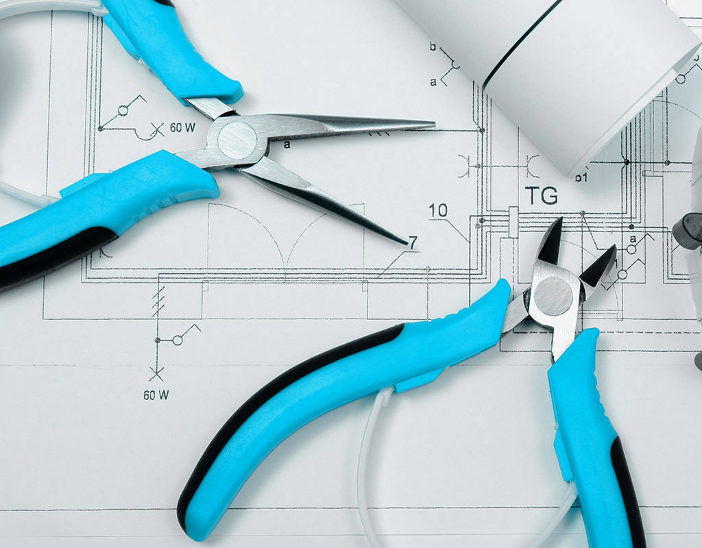 Electrical tools like pliers and cutters laid out on blueprints by Mulholland Electric Inc in San Francisco, CA.