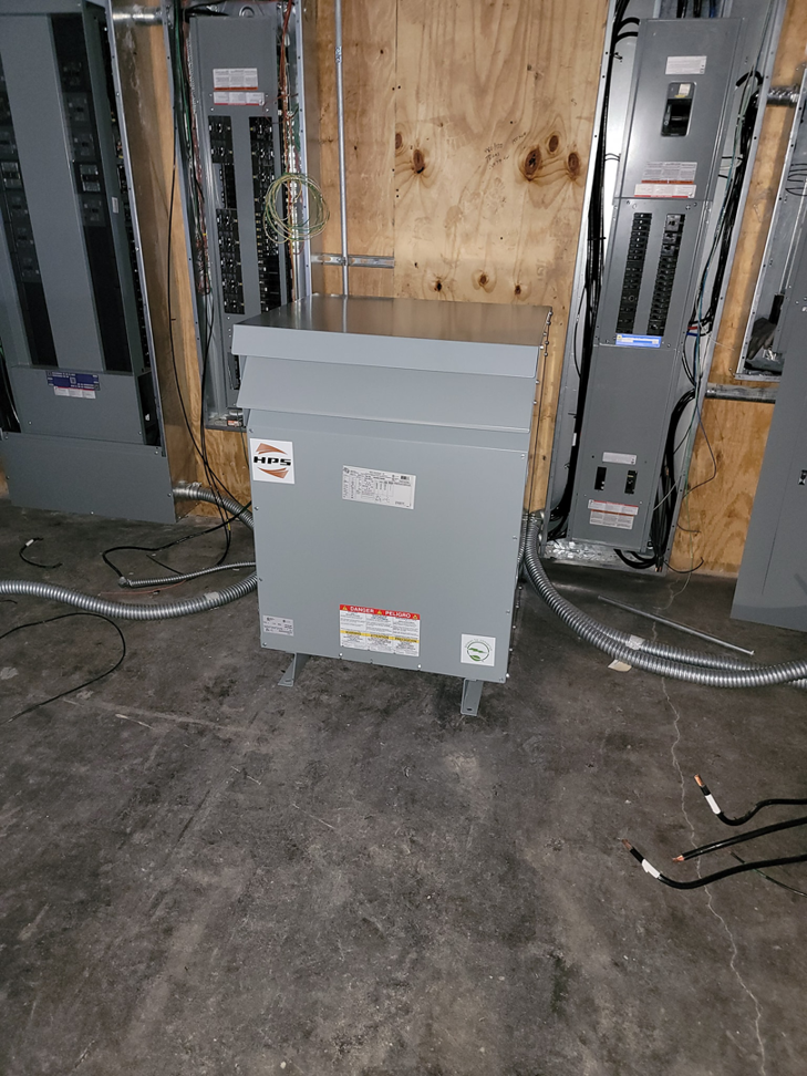 A large electrical transformer and multiple circuit breaker panels in an electrical room by Trouble Shooters Electric Inc. in Pell City, AL