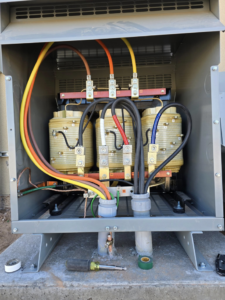 An open electrical transformer box with complex wiring and components, showing work by Desert Wind Electric in Albuquerque, NM