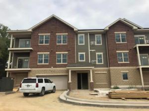 A green electrical utility box installed outside a new building at a construction site by Kadlec Electric Inc. in Elgin, IL.