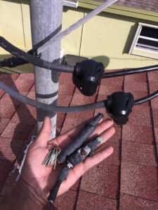 A hand holding old electrical wire connections, showing repair work by MG ELECTRIC INC in Lauderhill, FL