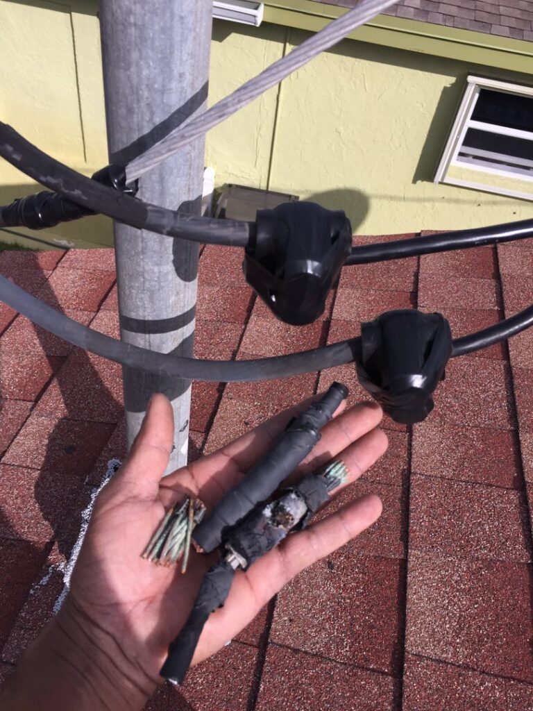 A hand holding old electrical wire connections, showing repair work by MG ELECTRIC INC in Lauderhill, FL