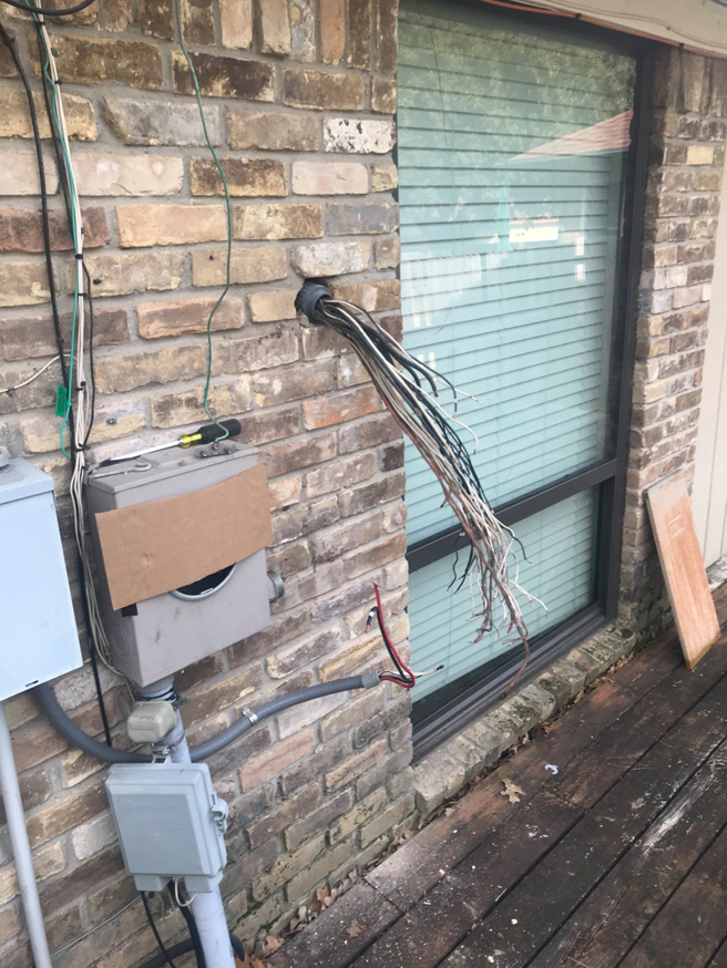 Electrical wires emerging from a conduit on a brick wall, installed by Pressed Down Electric LLC in Rockwall, TX.