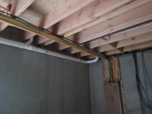 Electrical wiring running along ceiling joists and a concrete wall, installed by Safehouse Electric Company in Blue Springs, MO.
