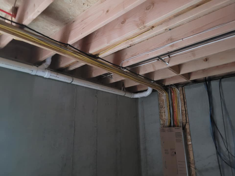 Electrical wiring running along ceiling joists and a concrete wall, installed by Safehouse Electric Company in Blue Springs, MO.