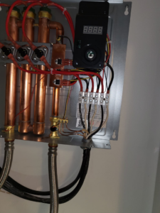 Close-up of electrical wiring and copper pipes inside a tankless water heater installed by Delta Electric in Germantown, MD.