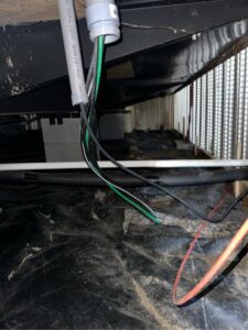 Electrical wiring and conduit visible under a house or deck structure, indicating installation or maintenance by Legacy Electric in Westminster, CO.