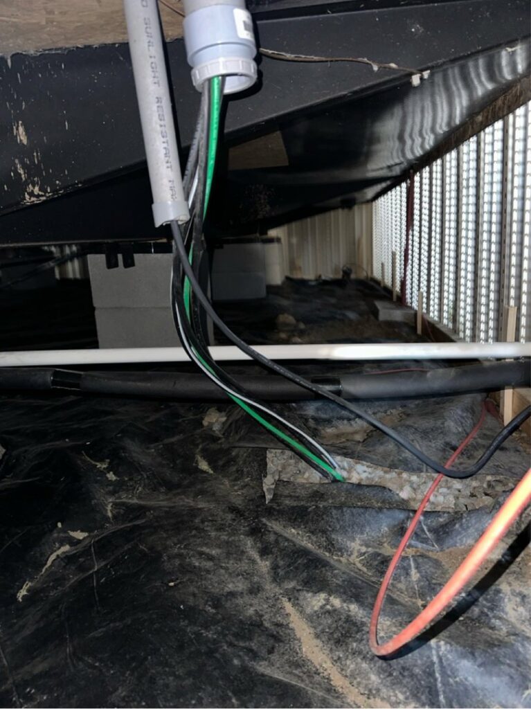 Electrical wiring and conduit visible under a house or deck structure, indicating installation or maintenance by Legacy Electric in Westminster, CO.