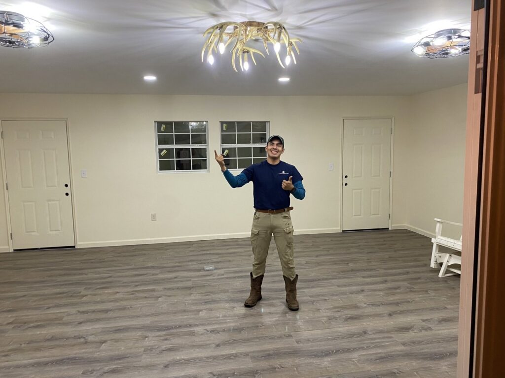 An Ultralight Electrician giving a thumbs up after completing a lighting fixture installation in a new room in Houston, TX.