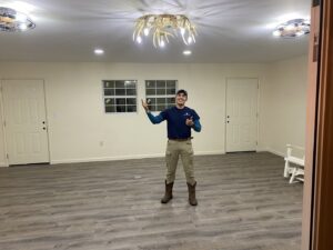 An Ultralight Electrician giving a thumbs up after completing a lighting fixture installation in a new room in Houston, TX.