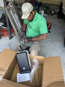 An electrician from Green Volt Electric LLC assembling an EV charging station component in a garage in Durham, NC.