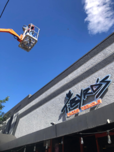 An electrician in a boom lift performing commercial sign repair for a business, provided by JJRS Electrical, LLC in Colorado Springs, CO.