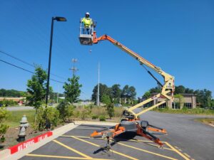 An electrician in a boom lift performing outdoor light pole repair, a service offered by 8Thirty Electric, Inc. in Johns Creek, GA.