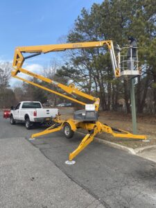 An electrician working from a boom lift on an outdoor pole, performing electrical service for New York Electrical Design in Freeport, NY