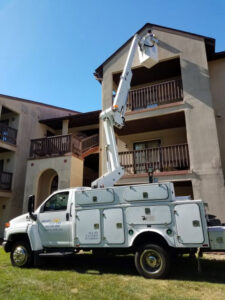 An electrician in a bucket truck repairing an exterior light for Bright Electric in Evansville, IN.