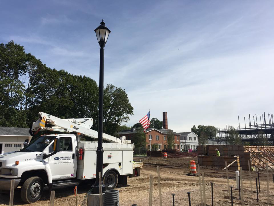 A Pasquariello Electric Corporation bucket truck next to a streetlight pole installation on a construction site in New Haven, CT.